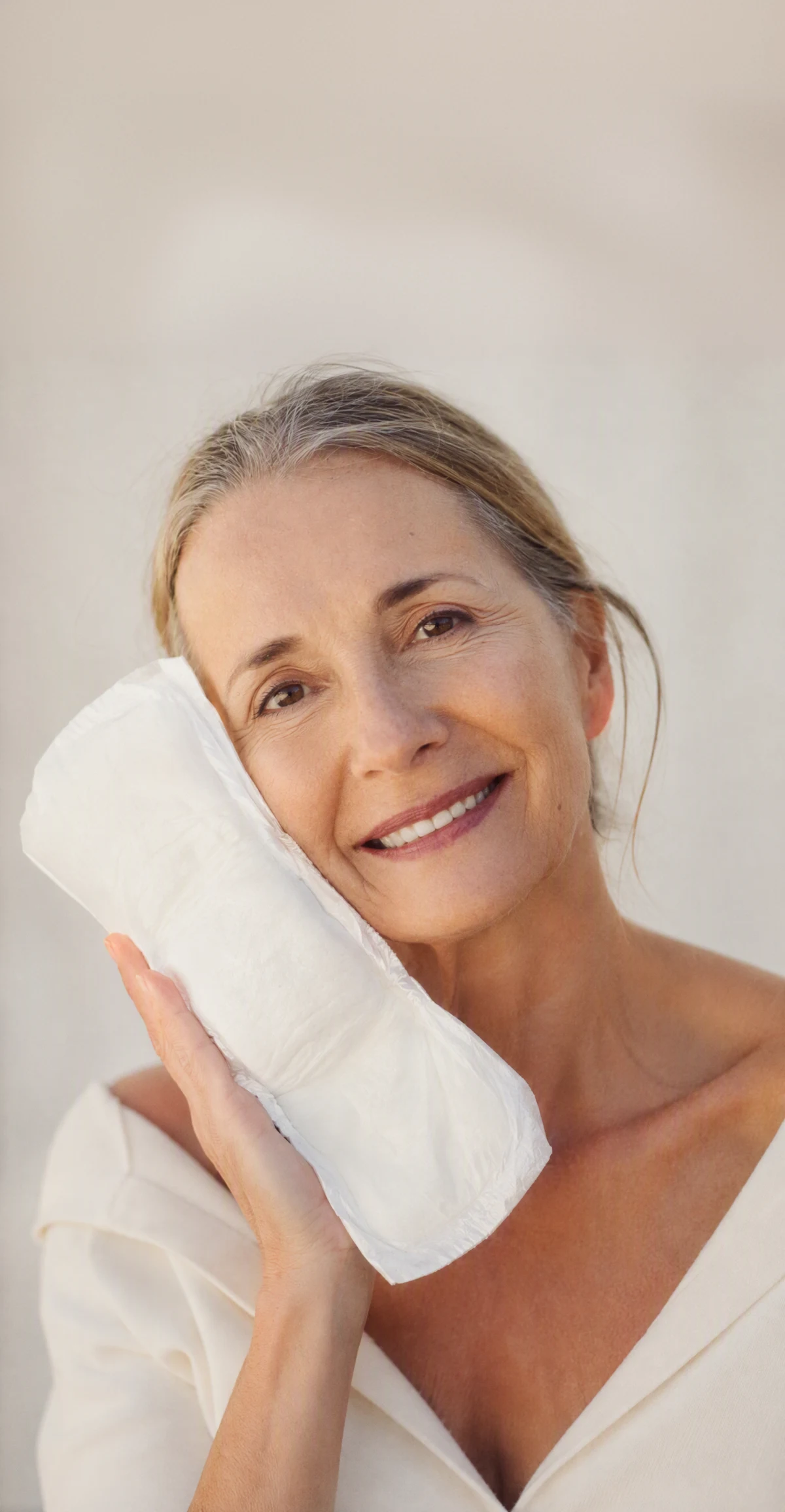 A woman holding an Attn: Grace pad against her cheek